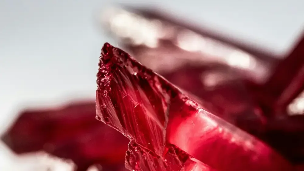 a close up of some red crystals on a white surface